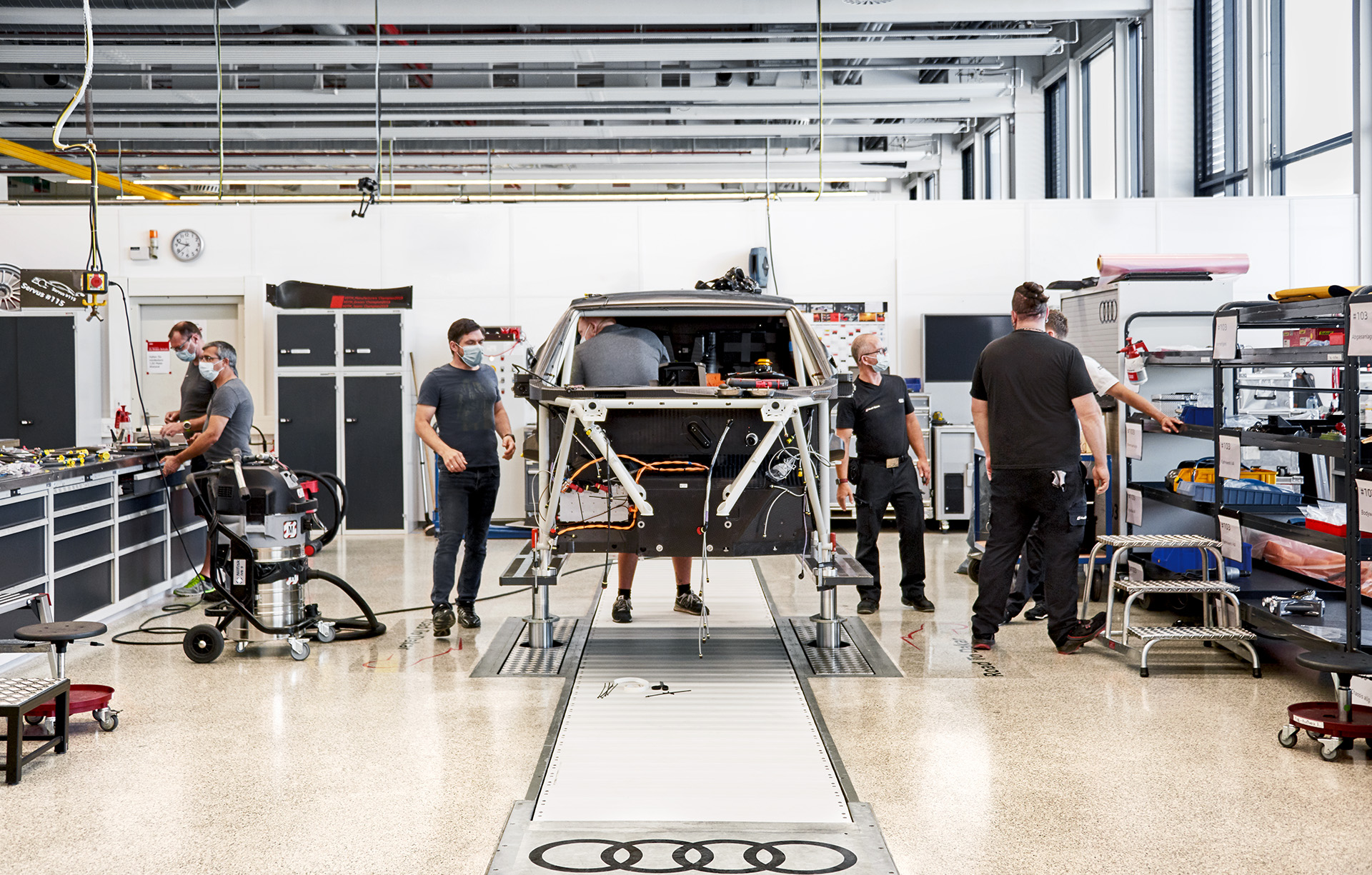 Audi Sport-ansatte jobber på rallybilens forhøyede bur på et verksted.
