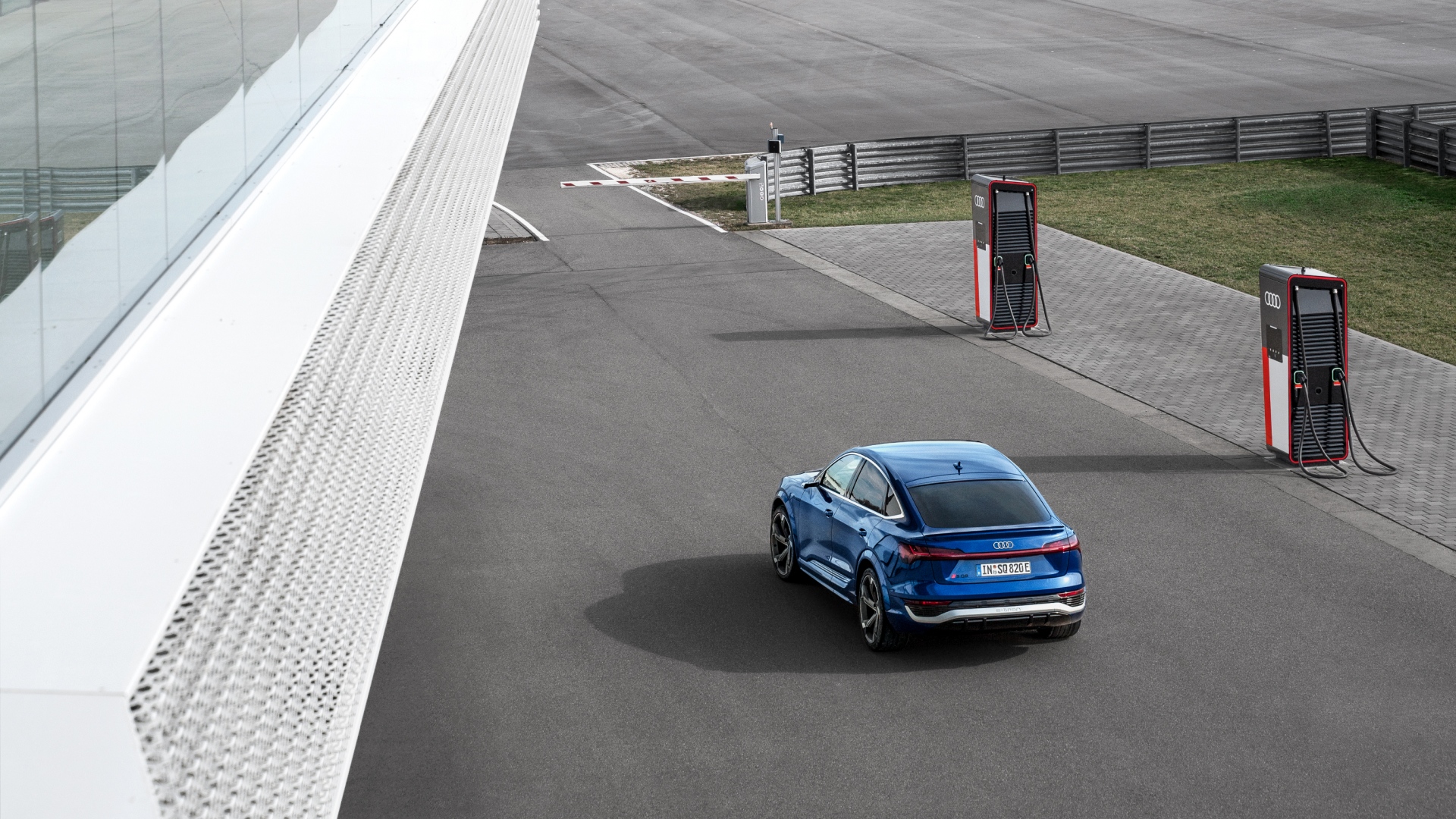 Audi SQ8 Sportback e-tron foran flere ladestasjoner.