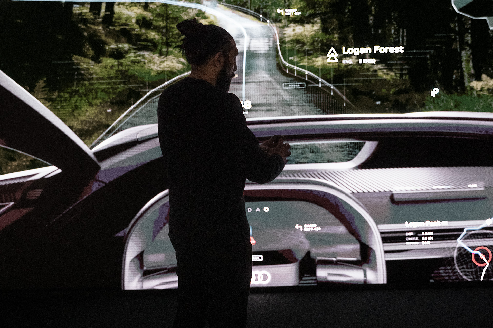 Sid Odedra foran en projisert førerplass i en bil.